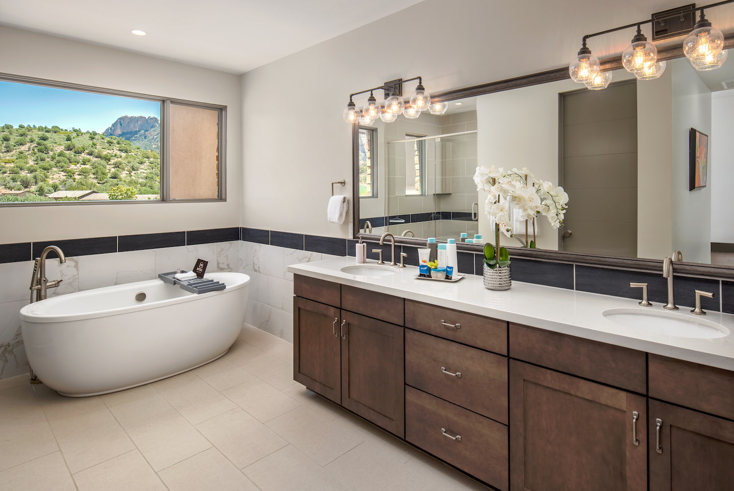 Luxury bathroom with dual vanity, modern soaking tub, and a view of the mountains.